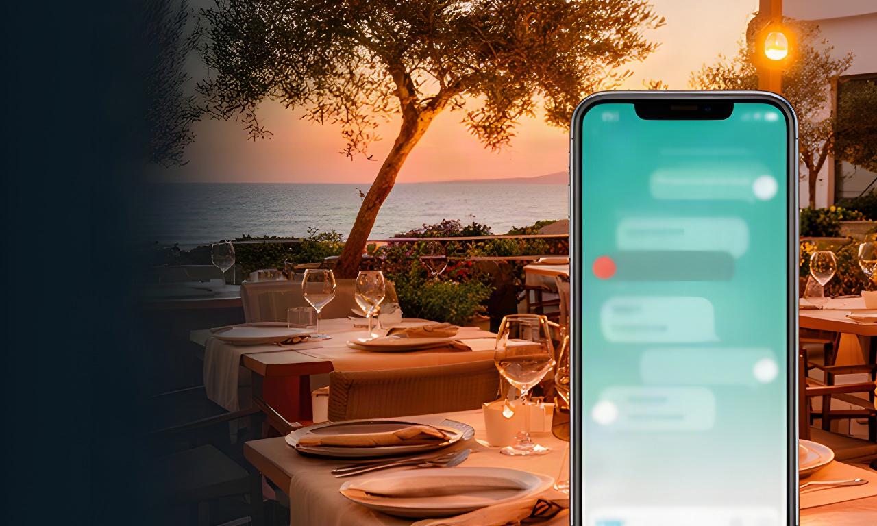Terraza mediterránea de un restaurante en Vinaròs al atardecer, con un móvil mostrando un chat de bienvenida